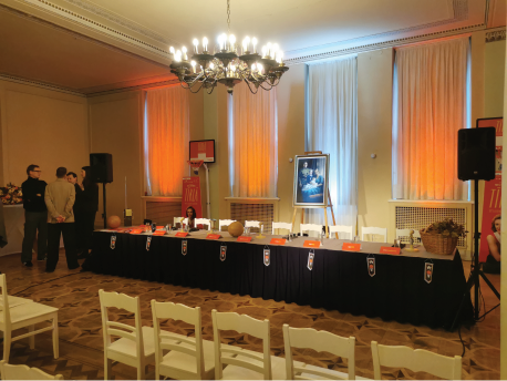 Preses konferences skatuve ar gaismu akcentiem un TTT komandas fona sienu